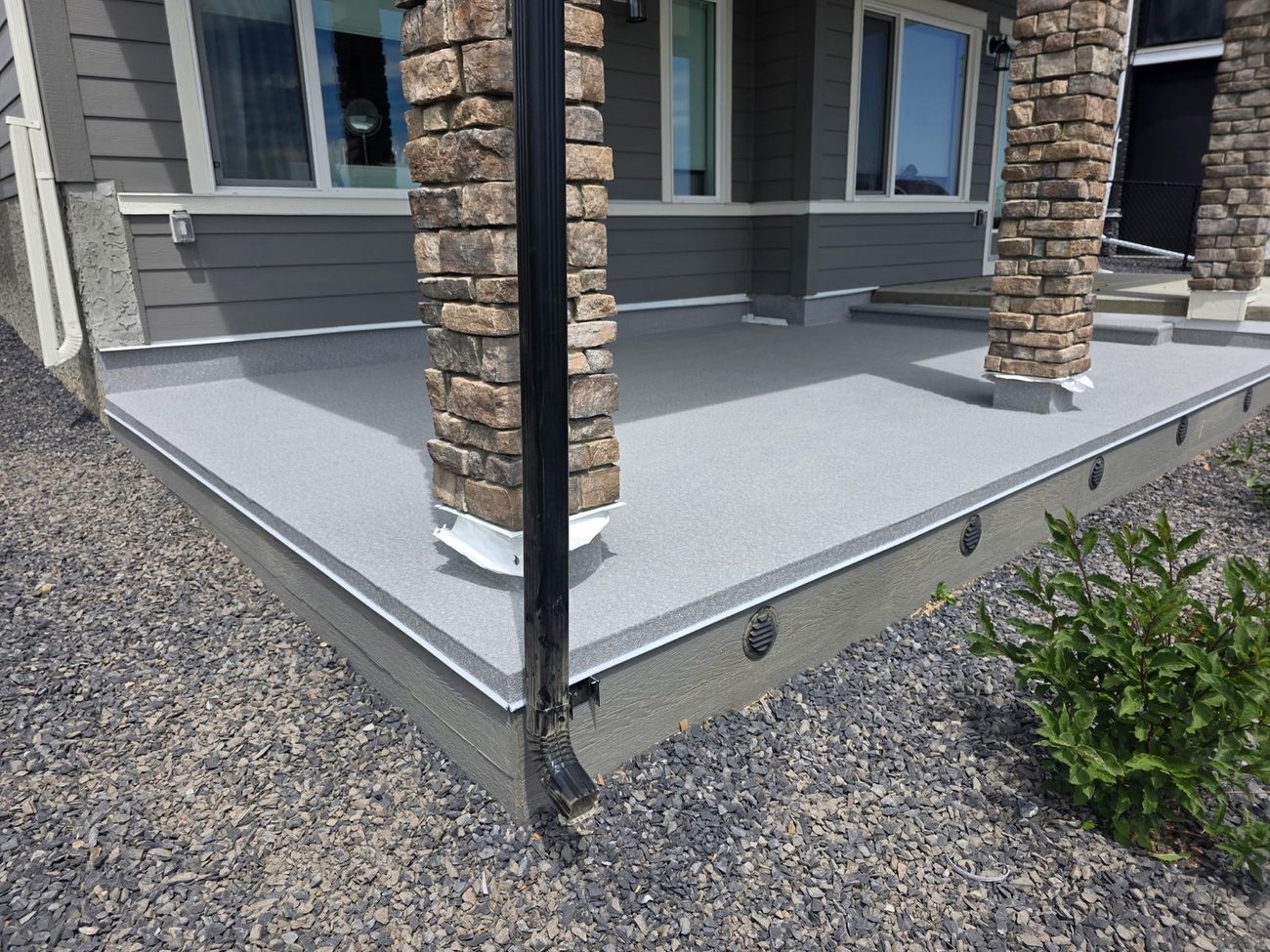 Vinyl membrane deck with cultured stone columns on a new home