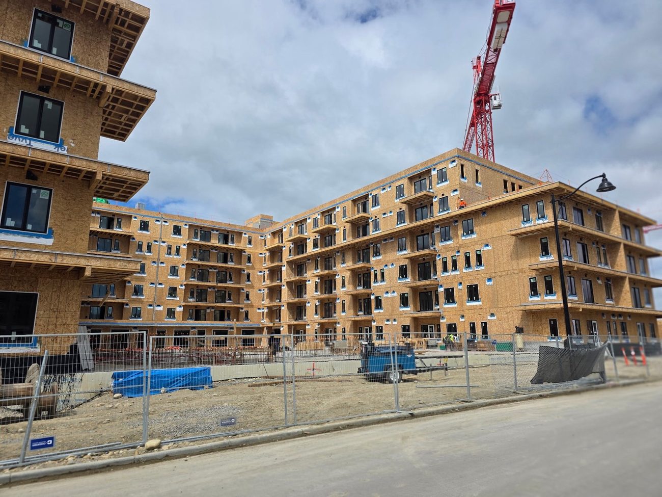 Six-storey U-shaped wood-frame apartment with tower crane
